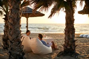 zwei Personen am Strand unter einem Sonnenschirm in der Unterkunft ROBINSON KYLLINI BEACH - All Inclusive in Kyllini