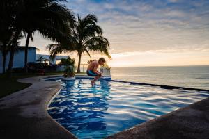 a man kneeling in a swimming pool next to the ocean at Hotel Vistalmar in Manta