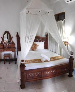 sypialnia z drewnianym łóżkiem z baldachimem w obiekcie Praety Home Stay w mieście Ubud