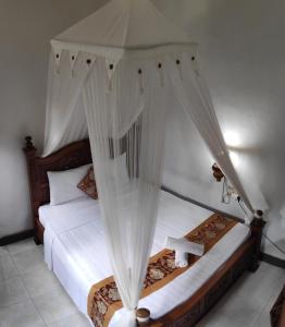 sypialnia z łóżkiem z baldachimem i białymi zasłonami w obiekcie Praety Home Stay w mieście Ubud