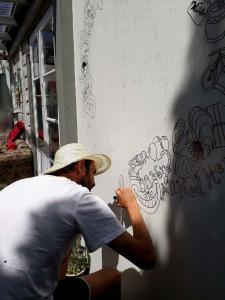 Un uomo con un cappello che scrive su un muro di Jack's Backpackers a Blenheim