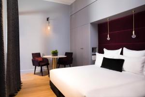 Un dormitorio con una gran cama blanca y una mesa en Hôtel Cardinal Bordeaux Centre, en Burdeos