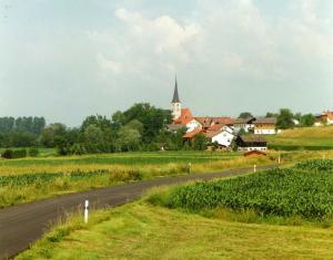 uma estrada que leva a uma aldeia com uma igreja em Gasthof zum Kirchenwirt em Kirchdorf am Inn