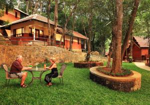 Ein Mann und eine Frau sitzen an einem Tisch im Garten in der Unterkunft Vythiri Resort in Vythiri