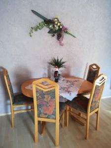 a dining room table and chairs with a flower arrangement on the wall at Ferienwohnung Preuß in Martinlamitz