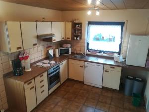 a small kitchen with white cabinets and a window at Ferienwohnung Preuß in Martinlamitz