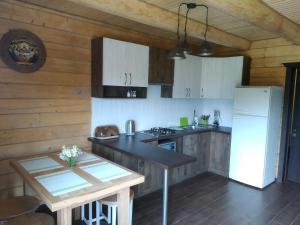 cocina con armarios blancos, mesa y nevera en Пагорб Їжака / Hedgehog Hill, en Yablunytsya