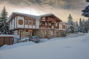 een huis in de sneeuw met een auto voor de deur bij MPM Family Hotel Merryan in Pamporovo