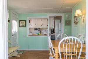 een keuken met groene muren en een tafel en stoelen bij The Eastern Avenue Cottage in Wells Beach