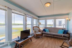 een woonkamer met een bank, een tv en ramen bij The Eastern Avenue Cottage in Wells Beach