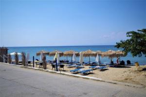 una playa con sombrillas y sillas y el océano en Sotiras Rooms, en Skala Sotiros