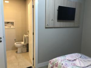 bagno con servizi igienici e TV a parete di Piemont Hotel a Curitiba