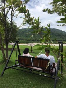 duas pessoas sentadas num baloiço num parque em Samerdrow Khao Yai em Mu Si