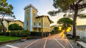 une maison jaune avec une tour d'horloge dans une rue dans l'établissement Hotel Ville Bianchi, à Grado