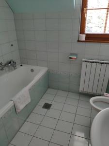 ein weißes Badezimmer mit einer Badewanne und einem Waschbecken in der Unterkunft Antela, 142 m2 appartment for 12 person in Mariborsko Pohorje in Hočko Pohorje