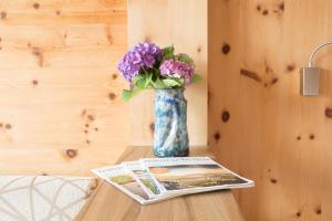 een vaas met paarse bloemen op een tafel met een tijdschrift bij Hotel Appartement Inge in Tirolo