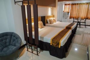 um quarto com duas camas e uma cadeira. em North Tourist Inn em Bacolod