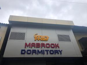 een bord aan de zijkant van een gebouw met een macrophoryopathie bord bij Mabrook Dormitory in Mumbai