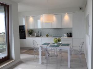 una cucina bianca con tavolo e sedie bianchi di Apartament Sea Towers View a Gdynia