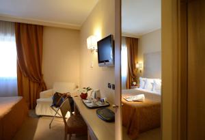 a hotel room with two beds and a desk with a television at Best Western Hotel Rome Airport in Fiumicino