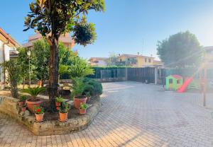 a group of potted trees in a courtyard with a playground at 32 in Ciampino