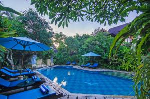 een zwembad met blauwe stoelen en parasols bij Sri Phala Resort & Villa in Sanur