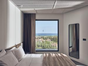 a bedroom with a bed and a large window at Zante Maris Suites - Adults Only in Tsilivi