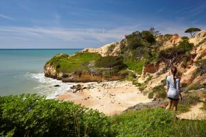 Una mujer parada en un acantilado mirando el océano en PortoBay Falesia, en Albufeira