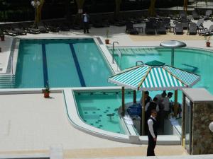 um homem debaixo de um guarda-chuva ao lado de uma piscina em Hotel Nufarul em Baile Felix