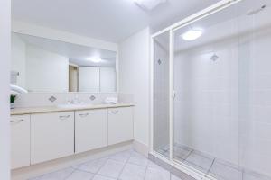 a white bathroom with a shower and a sink at Atlantis Marcoola in Marcoola