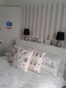 un letto con lenzuola e cuscini bianchi di South Rising Guest House a Poole