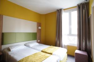 pokój hotelowy z 2 łóżkami i oknem w obiekcie Hôtel De France w mieście Boulogne-Billancourt