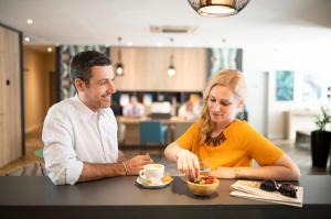 Een man en een vrouw die aan een tafel eten. bij Three Corners Lifestyle Hotel in Boedapest