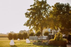 a garden with white benches and a tree and a house at Gutshof Sagmühle in Bad Griesbach