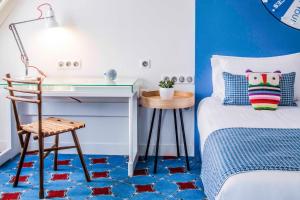 Schlafzimmer mit einem Schreibtisch und einem Bett mit blauen Wänden in der Unterkunft Hotel Joke - Astotel in Paris