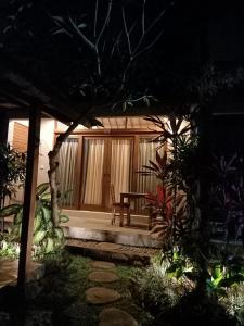 un patio por la noche con una mesa y una silla en Suka's House Bed & Breakfast, en Ubud