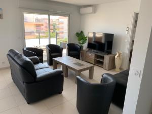 圣马克西姆Appartement 4 chambres LE BAIA的客厅配有桌椅和电视