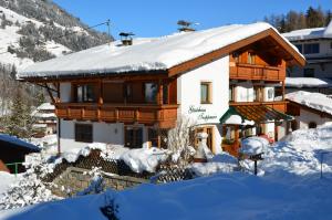 a house with a snow covered roof in the snow at Gästehaus Troppmair in Finkenberg