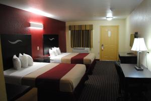 a hotel room with two beds and a desk at Scottish Inns Fort Worth in Fort Worth