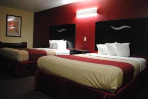 two beds in a hotel room with red walls at Scottish Inns Fort Worth in Fort Worth