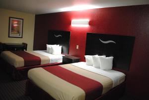 two beds in a hotel room with red walls at Scottish Inns Fort Worth in Fort Worth