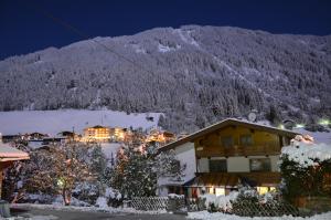 a house in the snow at night with a mountain at Gästehaus Troppmair in Finkenberg