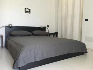 ein Schlafzimmer mit einem Bett mit einer grauen Tagesdecke in der Unterkunft VILLA AS Campo Marzio in Lenno