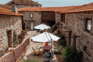 un patio esterno con tavoli e ombrelloni in un edificio di Casa de Louredo a Paredes