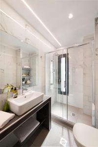 a white bathroom with a sink and a shower at Thess Residences in Thessaloniki