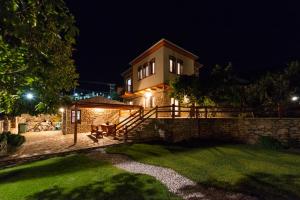 una casa de noche con una pared de piedra en Harmony Deluxe Villas, en Theológos