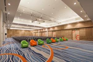 an empty conference room with green and orange chairs at HARRIS Hotel and Conventions Kelapa Gading Jakarta in Jakarta