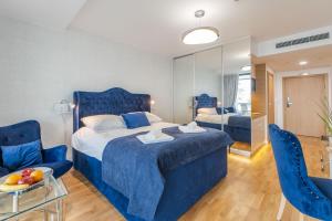 ein Hotelzimmer mit einem blauen Bett und einem Stuhl in der Unterkunft Seaside - Apartamenty KOMFORT, widok na morze, Parking in Kołobrzeg