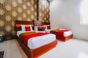 - une chambre avec 2 lits dotés de draps rouges et blancs dans l'établissement RedDoorz Plus @ Grand City Inn, à Makassar