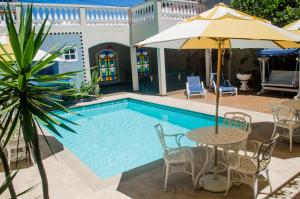 a pool with tables and chairs and an umbrella at Pousada Portal do Mar in Cabo Frio